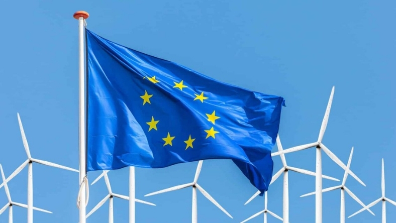 EU flag waving near renewable energy turbines