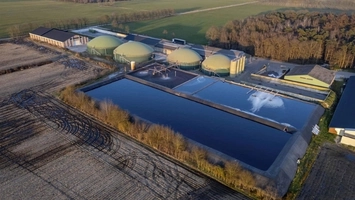 Biomethane plant with green dome digesters and rectangular lagoon surrounded by farmland