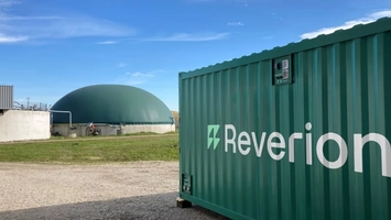 Reverion fuel cell container unit at a biogas plant with a dome digester and open landscape behind